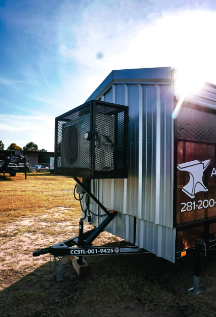 Exterior air conditioning unit in its protective cage mounted on the front wall of an Anvil Rentals trailer