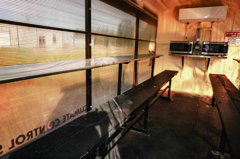 Interior of an Anvil Rentals climate-controlled trailer with bench seating, a bar-style counter, and two microwaves