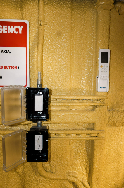 Interior light switch, power outlet, and air conditioning remote mounted on the insulated wall of an Anvil Rentals unit