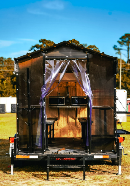 Rear entry of an Anvil Rentals lunchroom trailer looking in at the bench seating and two wall-mounted microwaves