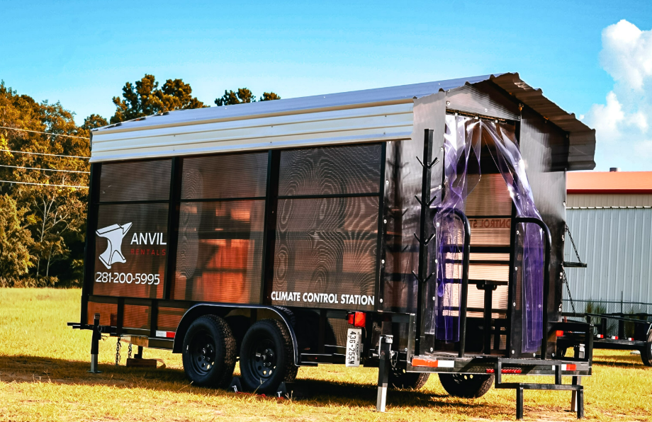 Angled view of an Anvil Rentals climate control station trailer showing the entry curtain and exterior hard hat tree